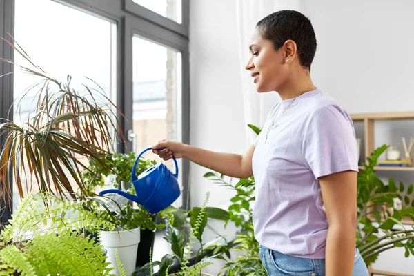 Afrikanska amerikanska kvinna vattna växter hemma — Stockfoto