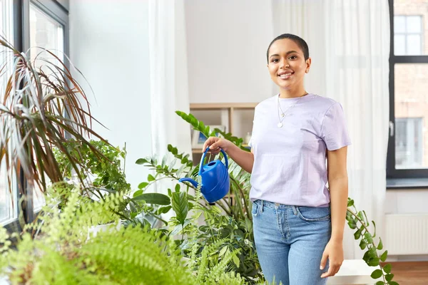 Afrikaans amerikaanse vrouw water geven planten thuis — Stockfoto