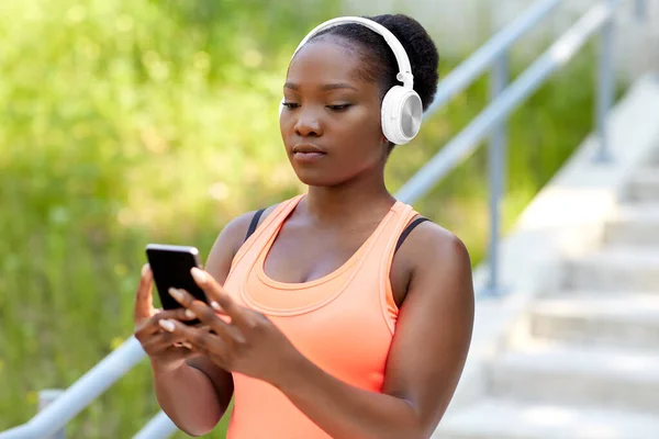 Afrikansk amerikansk kvinna med hörlurar och telefon — Stockfoto