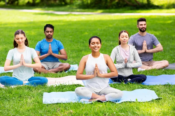 Grupp glada människor som gör yoga på sommarparken — Stockfoto