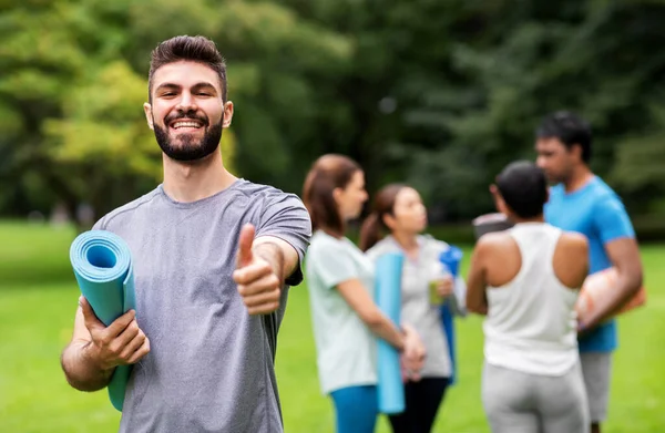 Sonriente hombre con esterilla de yoga mostrando los pulgares hacia arriba —  Fotos de Stock