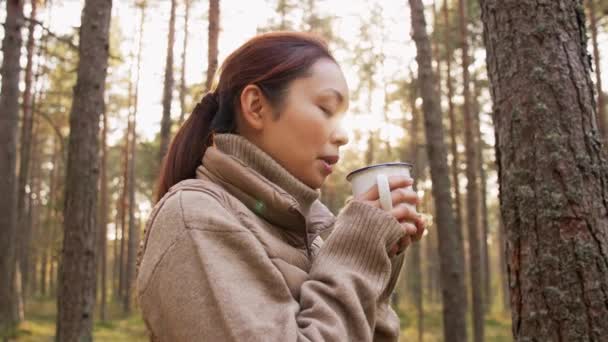 Asiatisk ung kvinna dricker varmt te i skogen — Stockvideo