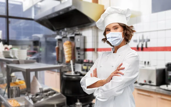 Cocinera en máscara con brazos cruzados en la cocina —  Fotos de Stock