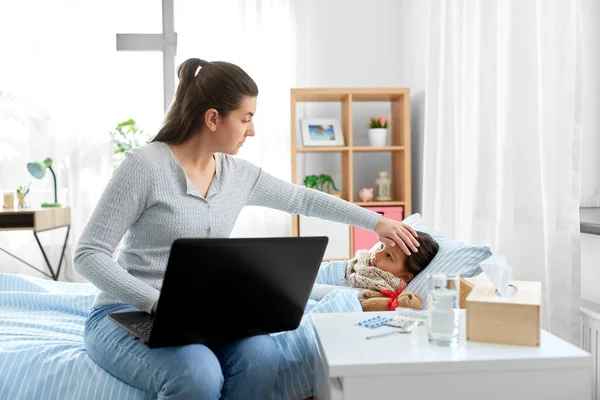 Filha doente e mãe com laptop em casa — Fotografia de Stock