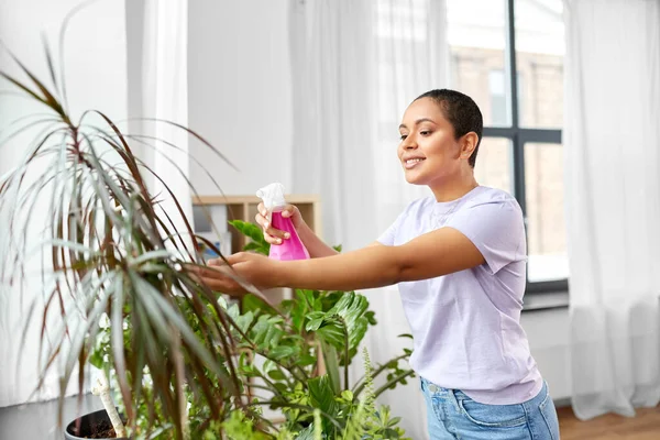 Mujer rociando planta de interior con agua en casa —  Fotos de Stock