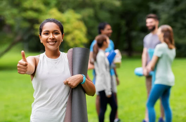 Smiling woman with yoga mat showing thumbs up — Stock Photo, Image