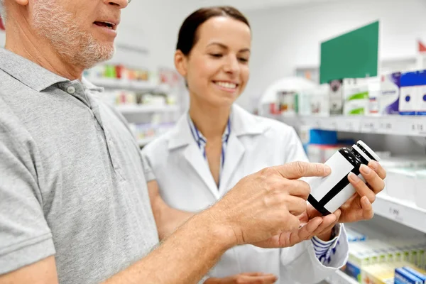 Фармацевт и старик с лекарствами в аптеке — стоковое фото