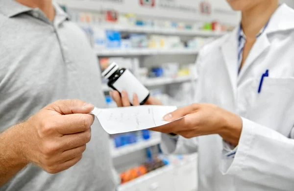 Farmacéutico y cliente con medicamentos en la farmacia —  Fotos de Stock