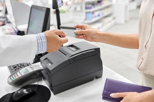 Close up de mão dando cartão bancário ao farmacêutico — Fotografia de Stock