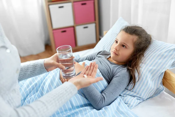 Mother giving medicine to sick little daughter — Stock Photo, Image