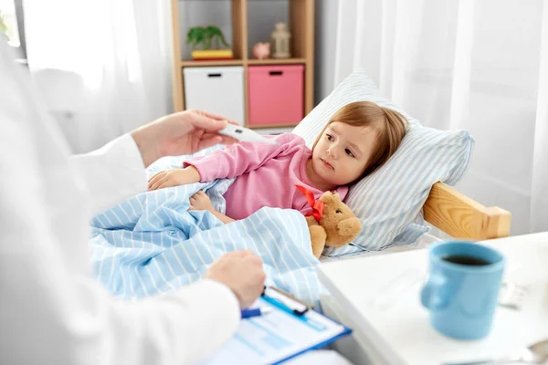 Doctor measuring sick girls temperature — Stock Photo, Image