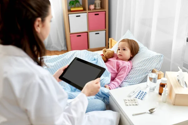 Doctor with tablet pc and sick girl in bed at home — Stock Photo, Image