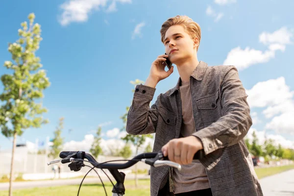 Młody człowiek z rowerem dzwoni przez telefon w mieście — Zdjęcie stockowe