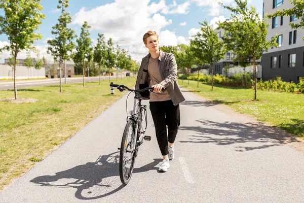자전거를 타고 도시의 거리를 걷고 있는 젊은이 — 스톡 사진