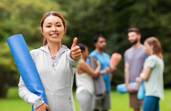 Mujer sonriente con esterilla de yoga mostrando los pulgares hacia arriba —  Fotos de Stock