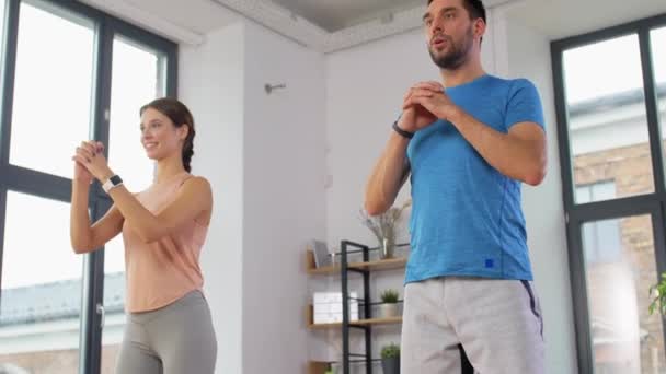 Feliz pareja haciendo ejercicio y haciendo sentadillas en casa — Vídeos de Stock