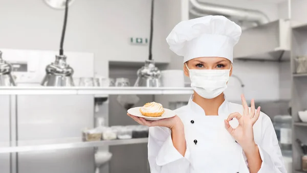 Kuchařka v masce s nápisem OK v kuchyni — Stock fotografie