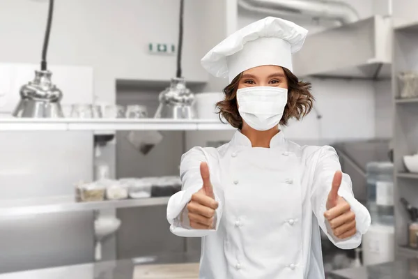 Femme chef en masque montrant pouces vers le haut à la cuisine — Photo