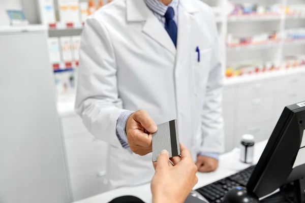 Close up de mão dando cartão bancário ao farmacêutico — Fotografia de Stock