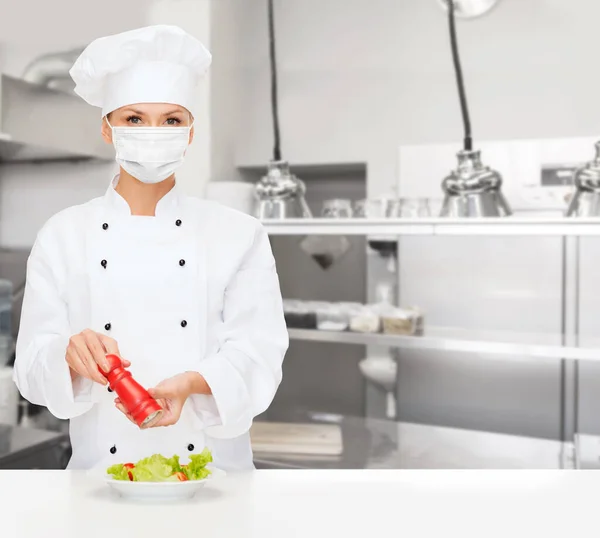 Vrouwelijke chef-kok in masker snijden groenten in de keuken — Stockfoto