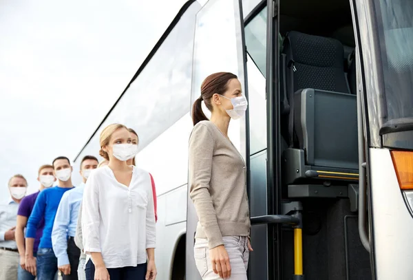 Skupina cestujících v maskách nastupujících do autobusu — Stock fotografie