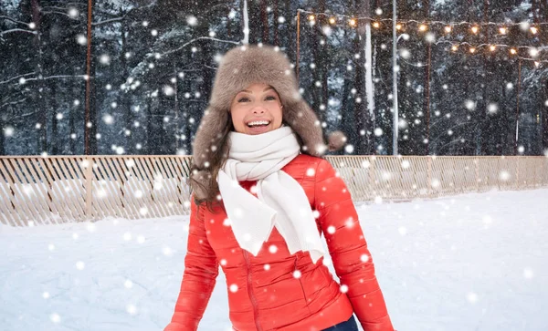 Glad kvinna i vinter hatt över skridskoåkning rinken — Stockfoto