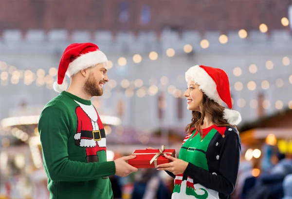 Feliz pareja en suéteres de Navidad con caja de regalo —  Fotos de Stock