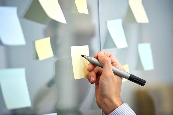 Hand with marker and sticker on glass at office — Stock Photo, Image