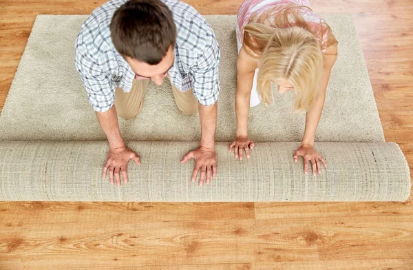 Lyckligt par rulla upp matta eller matta hemma — Stockfoto