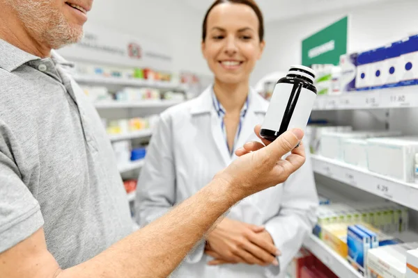 Farmacêutico e homem velho com medicina na farmácia — Fotografia de Stock