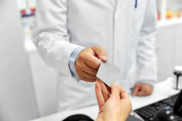 Close up de mão dando cartão bancário ao farmacêutico — Fotografia de Stock