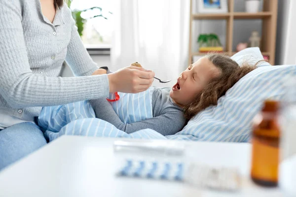 Madre dando jarabe para la tos a la hija enferma — Foto de Stock