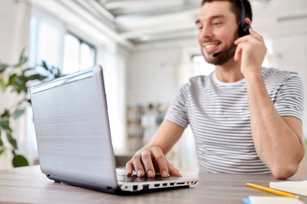 Man met headset en laptop thuis aan het werk — Stockfoto
