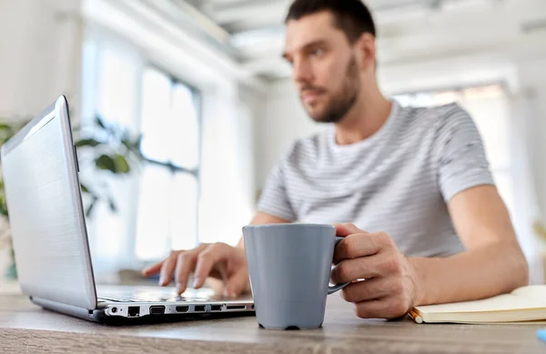 Man with laptop drinking coffee at home office — Stock Photo, Image