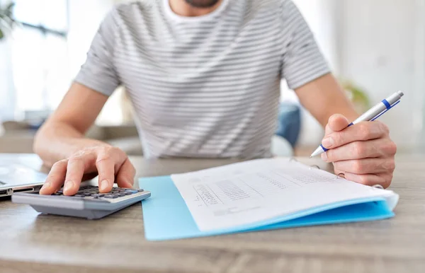 Mann mit Akten und Taschenrechner arbeitet im Homeoffice — Stockfoto