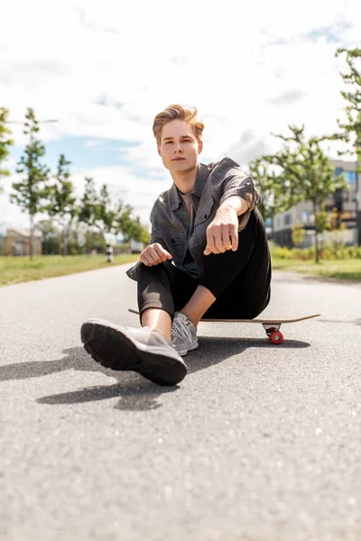 Έφηβος αγόρι κάθεται στο skateboard στην πόλη δρόμο — Φωτογραφία Αρχείου