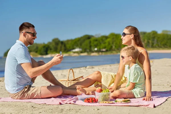 Семья со смартфоном на пляже — стоковое фото