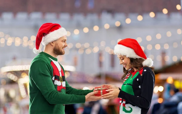 Happy couple in christmas sweaters with gift box — Stock Photo, Image