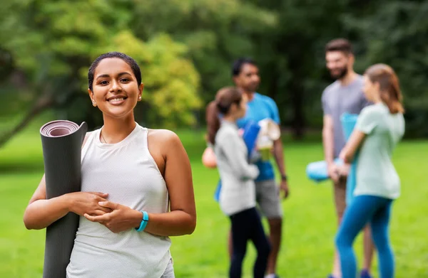 Mujer sonriente con esterilla de yoga sobre grupo de personas — Foto de Stock