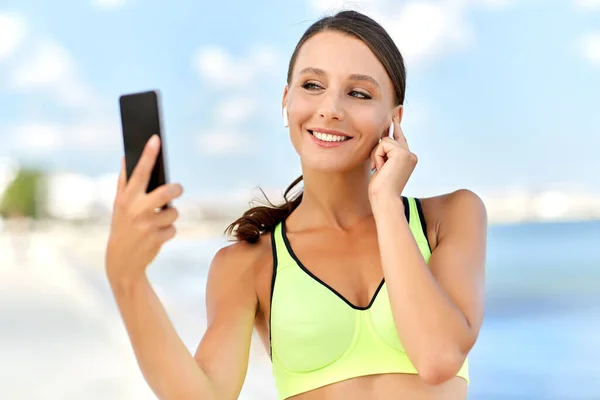 Donna con auricolari e smartphone fare sport — Foto Stock