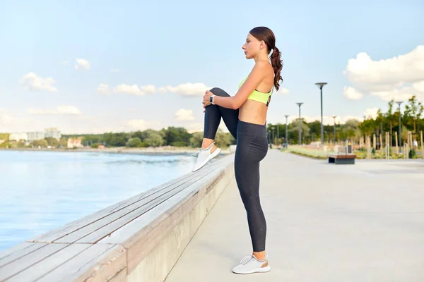 Spor yapan ve bacak esneten mutlu genç bir kadın. — Stok fotoğraf