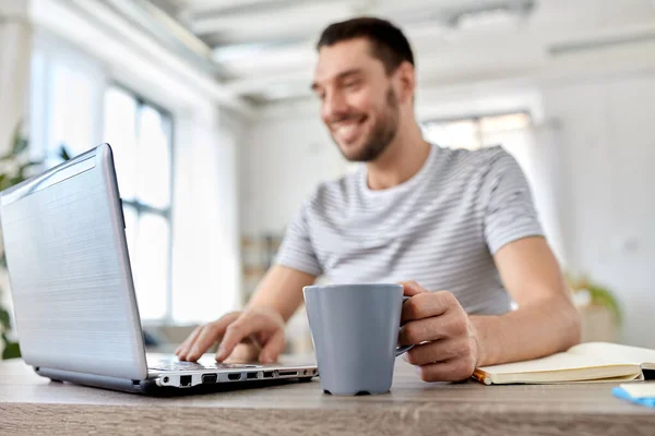 Homem feliz com laptop beber café em casa Imagens Royalty-Free