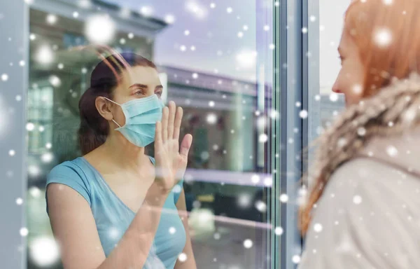 Mujer enferma en la máscara mirando amigo a través de la ventana —  Fotos de Stock