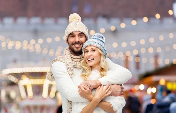 Koppel in de winter knuffelen over kerstmarkt — Stockfoto