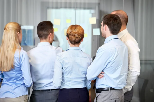 Business team with sticky notes on glass at office — Stock Photo, Image