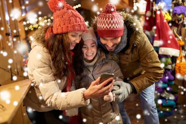 Lycklig familj med smartphone på julmarknaden — Stockfoto