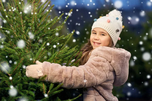 Niña eligiendo el árbol de Navidad en el mercado —  Fotos de Stock