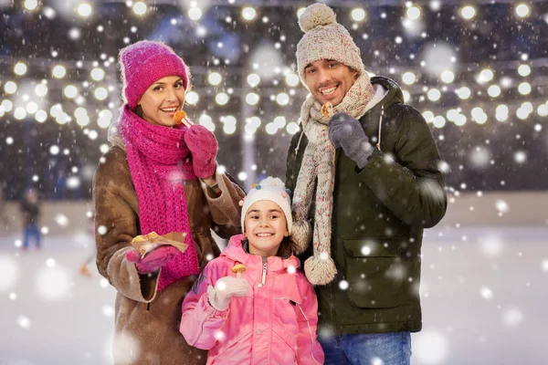 Familia feliz comiendo panqueques en pista de patinaje — Foto de Stock