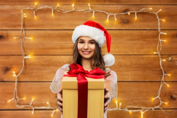Tonårstjej i tomte hatt med julklapp — Stockfoto