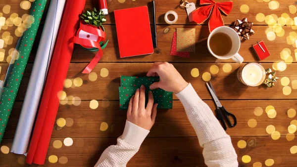 Mãos embrulhando presente de Natal em papel em casa — Fotografia de Stock